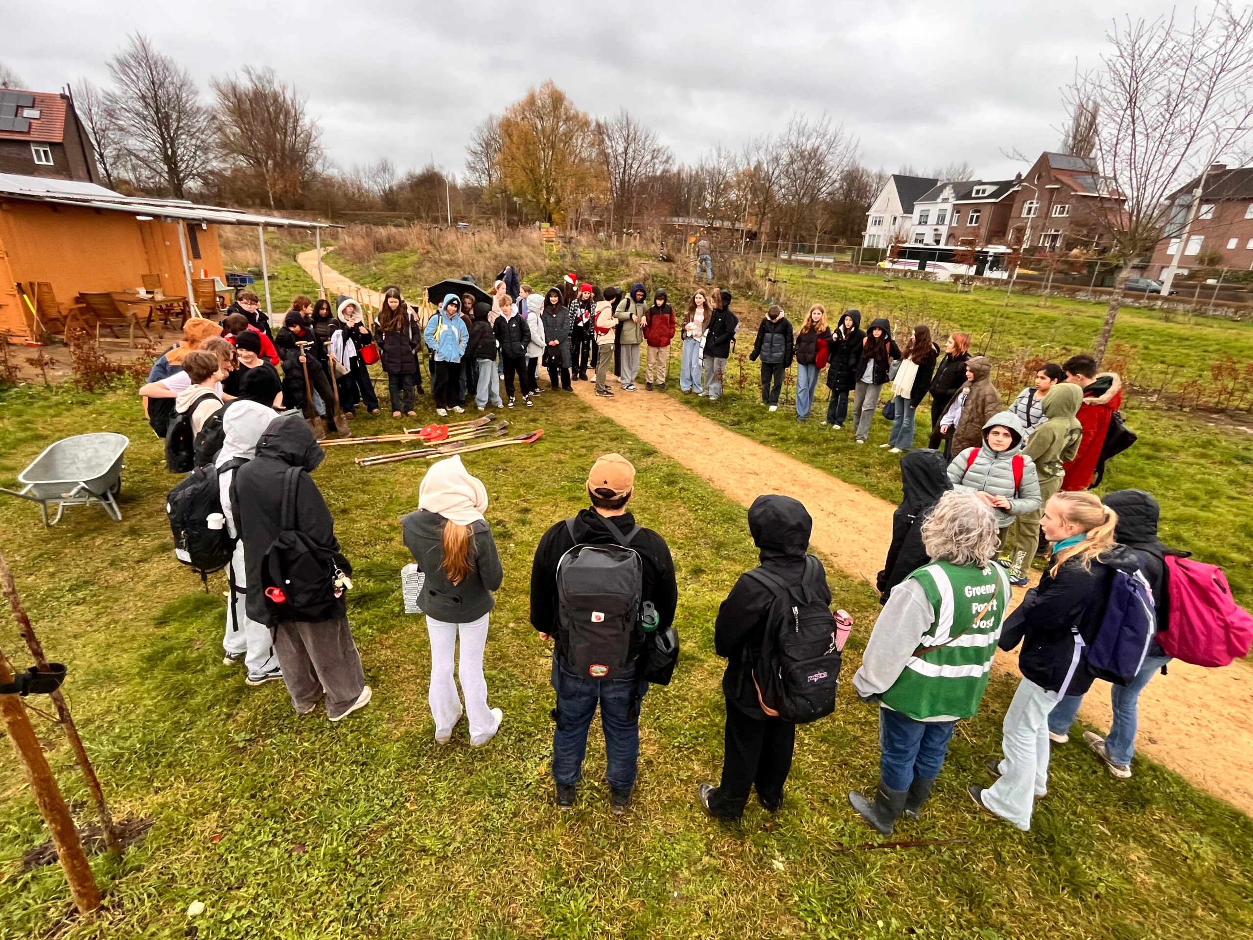Tientallen leerlingen van het UWC staan in het park in een cirkel rondom vrijwilligers van de groene poort. Ze krijgen uitleg.