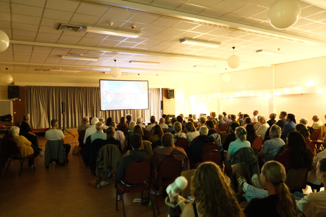 Filmavond 2026 Zaal met groot filmscherm en publiek op stoelen.