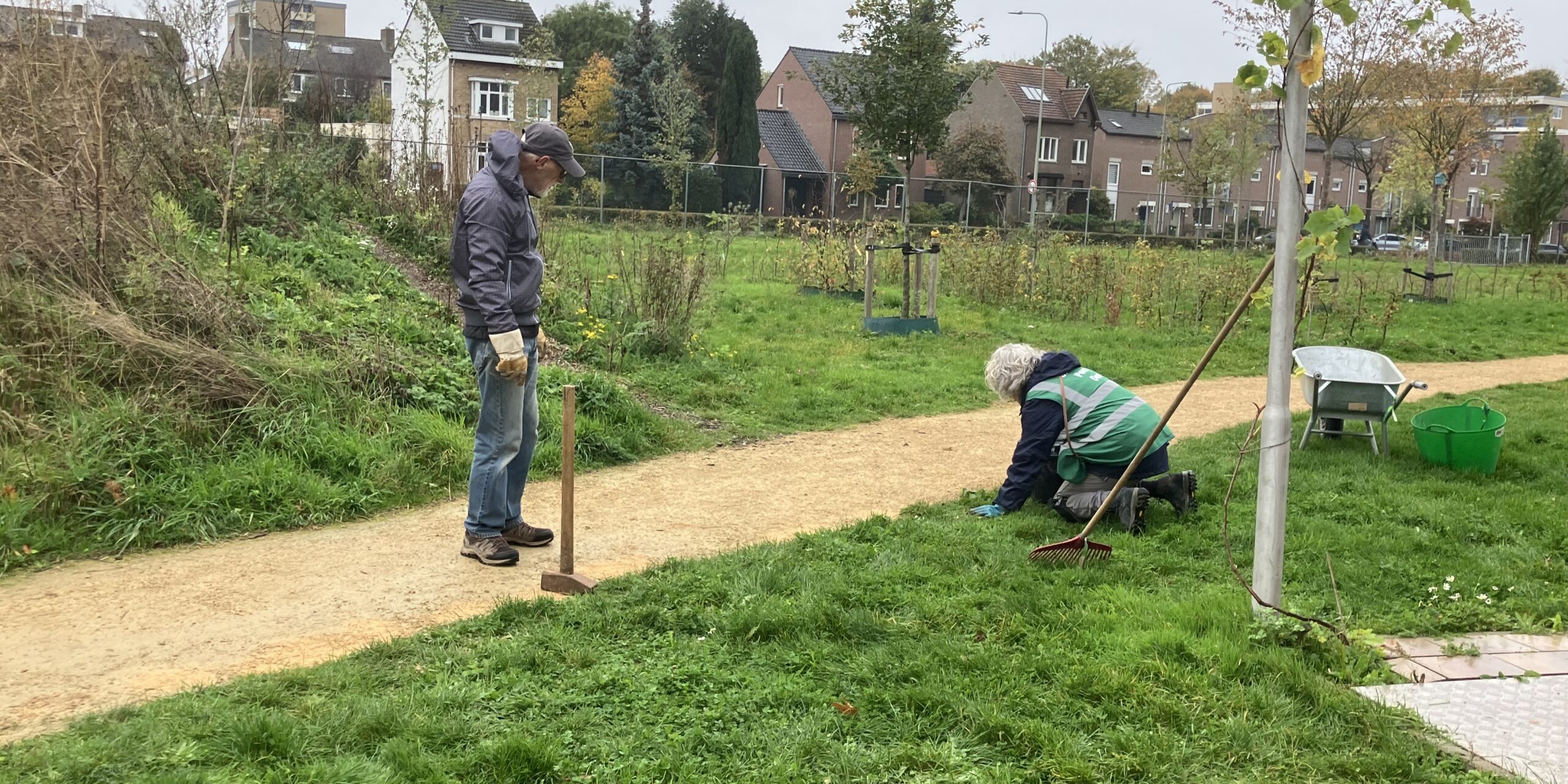 Twee vrijwilligers schoffelen de paden.