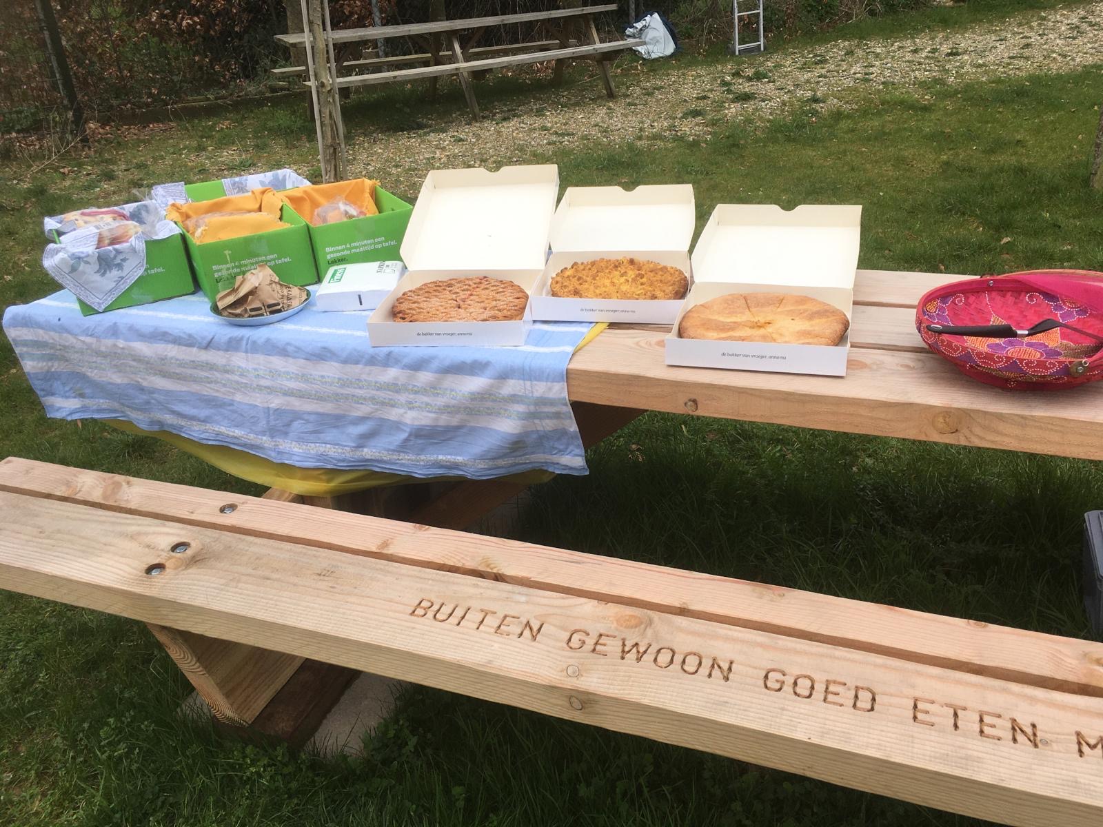 Picknick bank van PLUS. Op de tafel staan vlaaien.